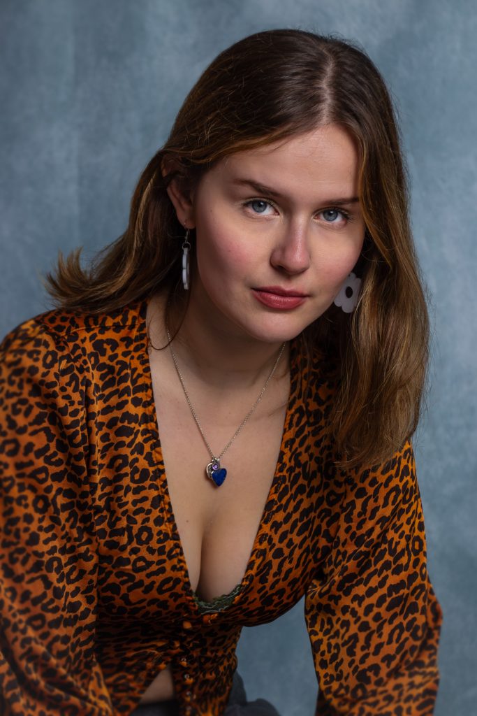 A woman with brown hair against a blue background